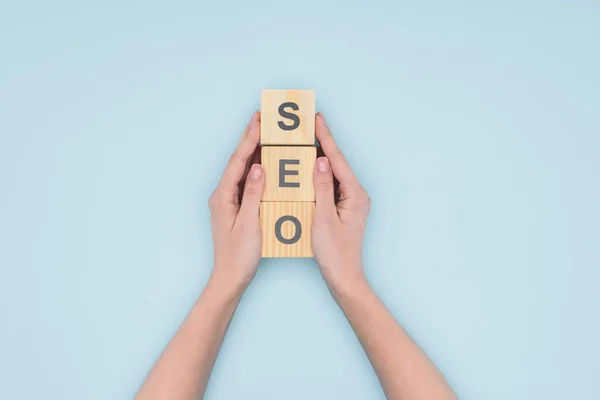 Top view of female seo manager holding wooden cubes on light blue background — Stock Photo