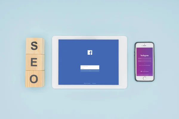Vista superior de dispositivos digitales con aplicaciones de Facebook e Instagram sobre fondo azul claro - foto de stock