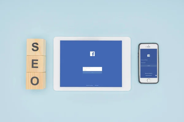 Vue du dessus des gadgets avec application facebook ouverte sur fond bleu clair — Photo de stock