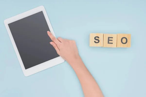 Top view of female seo manager pointing at gadget with blank screen on light blue background — Stock Photo