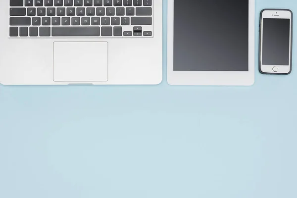 Top view of laptop, digital tablet and smartphone on light blue background — Stock Photo