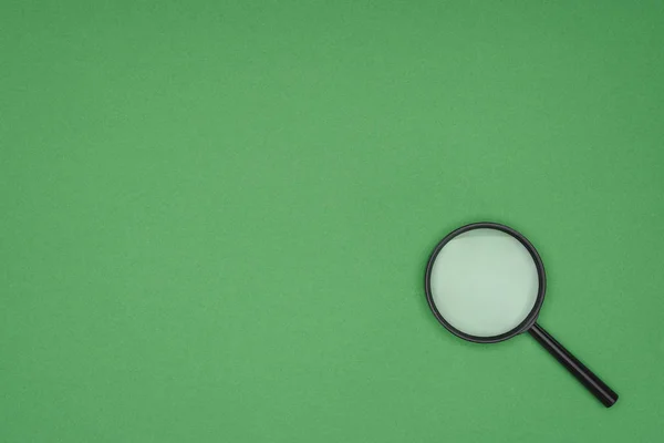 Top view of magnifying glass on green background — Stock Photo