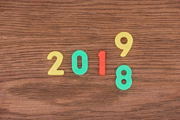 Top view of date made with colorful numbers symbolizing change from 2018 to 2019 on wooden background — Stock Photo