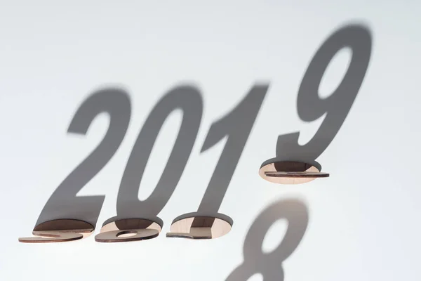 Ansicht von Holzzahlen mit Schatten auf weißem Hintergrund, die den Wandel von 2018 auf 2019 symbolisieren — Stockfoto