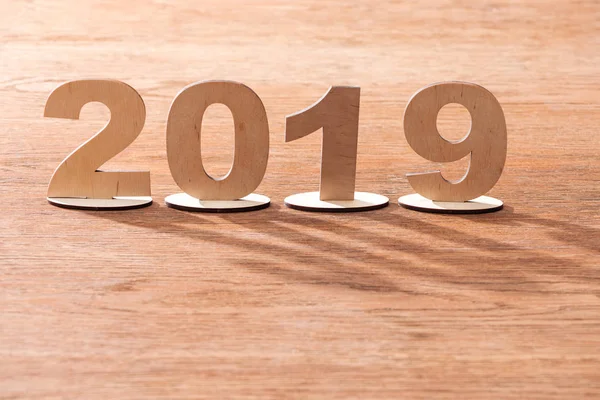 2019 date made of plywood numbers with shadows and copy space on wooden background — Stock Photo