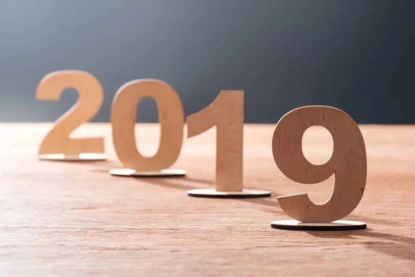 Дата 2019 года из фанеры на деревянном столешнице с черным фоном — стоковое фото