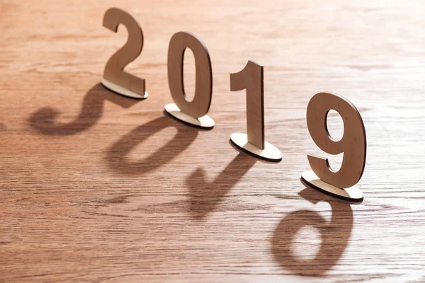 2019 date faite de nombres de contreplaqué avec des ombres sur la table en bois — Photo de stock