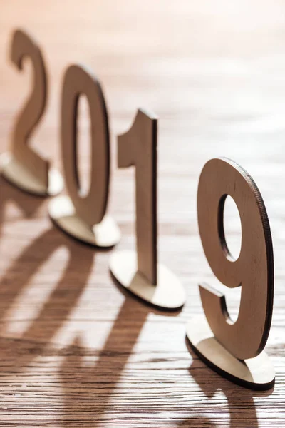 Дата 2019 года из фанерных чисел с тенями на деревянном столе — стоковое фото