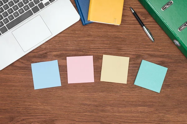 Top view of four sticky notes, laptop and office supplies on wooden desk — Stock Photo