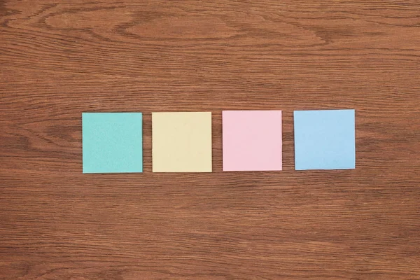 Top view of four sticky notes on wooden tabletop — Stock Photo