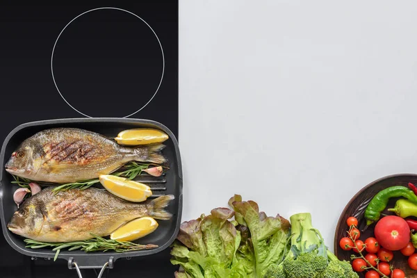 Top view of delicious fish with rosemary and lemon on grill and fresh vegetables on white — Stock Photo