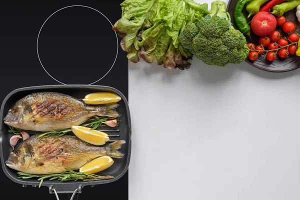 Vista superior de delicioso peixe frito com alecrim e legumes frescos em branco — Fotografia de Stock