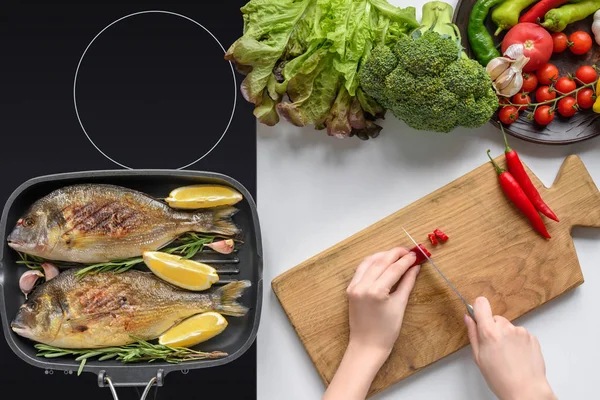 Cropped shot of person cutting chili pepper and cooking delicious fried fish — Stock Photo