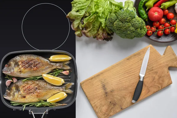 Vue du dessus de la planche à découper en bois avec couteau, légumes frais et poisson dorado frit — Photo de stock