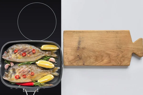 Vue de dessus de délicieux poissons frits sur cuisinière électrique et planche à découper en bois — Photo de stock