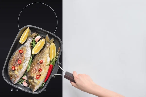 Abgeschnittene Aufnahme einer Person, die schmackhaften gebratenen Fisch mit Zitrone, Rosmarin und Kirschtomaten kocht — Stockfoto