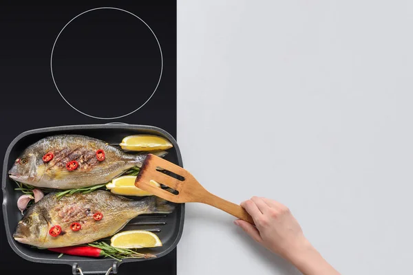 Tiro cortado de pessoa com utensílio de madeira cozinhar delicioso peixe frito — Fotografia de Stock