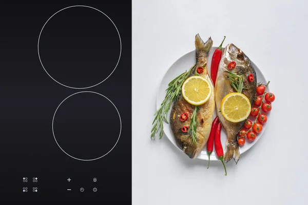 Top view of delicious fried fish with cherry tomatoes, rosemary, chili peppers and lemon on plate — Stock Photo