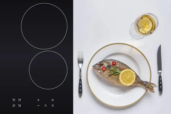 Вид вкусной жареной рыбы с лимоном и розмарином на тарелке и бокал вина на белом — стоковое фото
