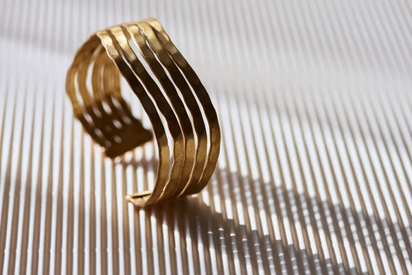 Primo piano di un bellissimo anello di lusso su una superficie bianca a strisce con luce solare — Foto stock