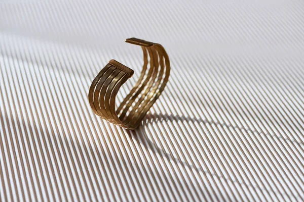 Красивое золотое кольцо на полосатой белой поверхности с солнечным светом — стоковое фото
