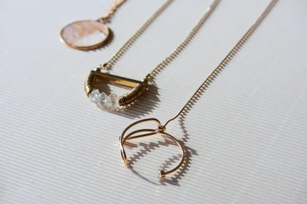 Close up de belos colares de luxo e medalhão redondo com mármore na superfície branca listrada com luz solar — Fotografia de Stock