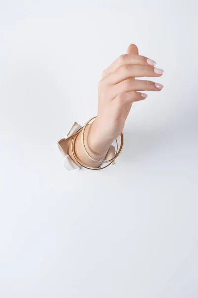 Cropped of image woman holding hand with beautiful bracelets through white paper — Stock Photo