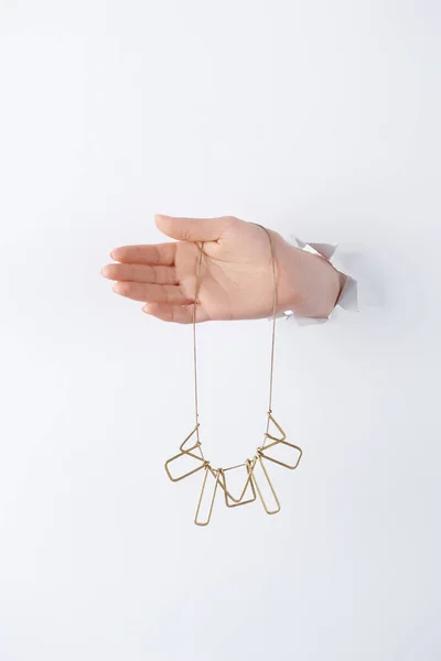 Cropped image of woman holding hand with beautiful golden necklace through white paper — Stock Photo