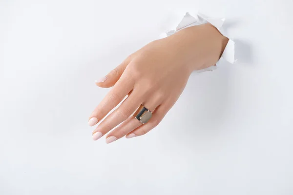 Immagine ritagliata della donna che si tiene per mano con un bellissimo anello di lusso attraverso carta bianca — Foto stock
