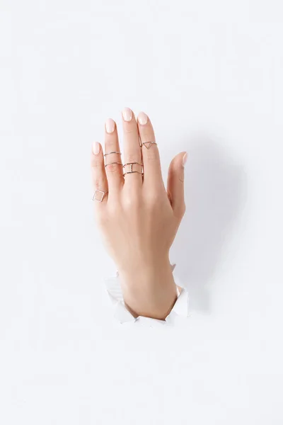 Cropped image of woman showing hand with beautiful luxury silver rings through white paper — Stock Photo