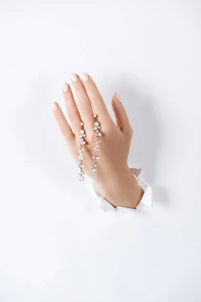 Обрезанное изображение женщины, держащей за руку красивый браслет с бриллиантами через белую бумагу — стоковое фото