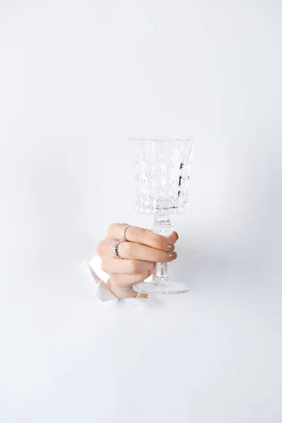 Cropped image of woman holding glass in hand with beautiful rings through white paper — Stock Photo