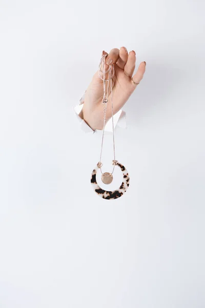 Imagen recortada de la mujer cogida de la mano con hermoso collar con estilo a través de papel blanco - foto de stock