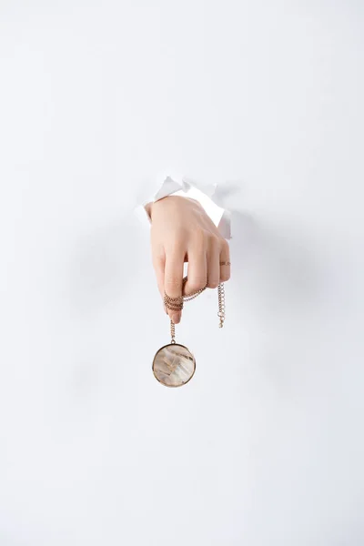 Cropped image of woman holding hand with beautiful luxury round locket with marble through white paper — Stock Photo