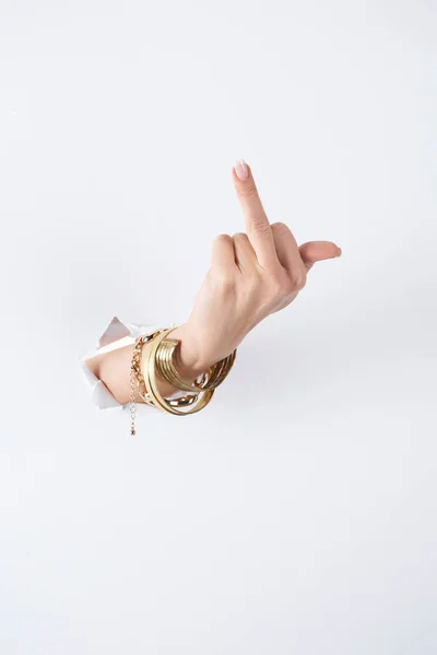 Cropped image of woman holding hand with bracelets through white paper and showing middle finger — Stock Photo