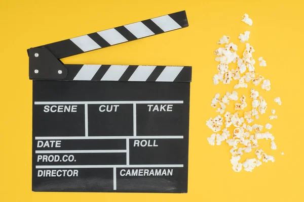 Top view of clapperboard and fresh crunchy popcorn isolated on yellow — Stock Photo