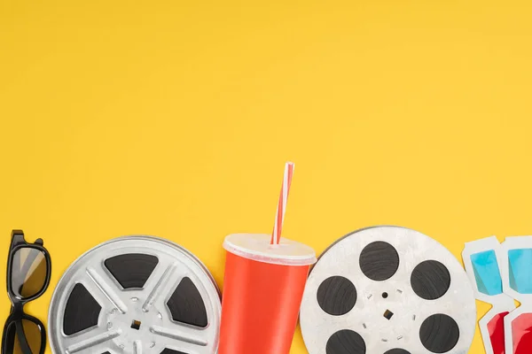 3d glasses, film reels and red disposable cup with straw isolated on yellow — Stock Photo