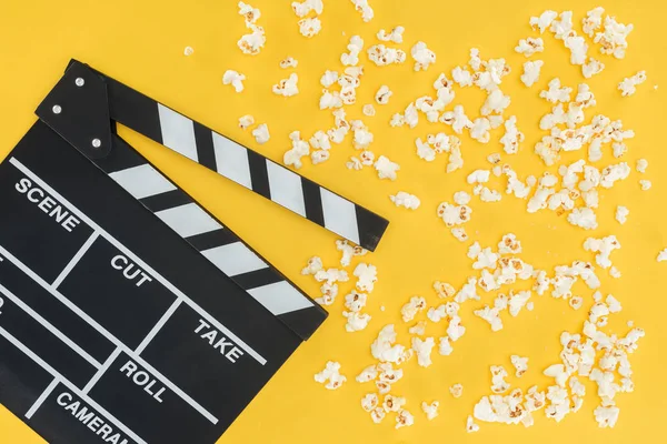 Vista superior do cinema clapperboard e pipoca crocante isolado no amarelo — Fotografia de Stock