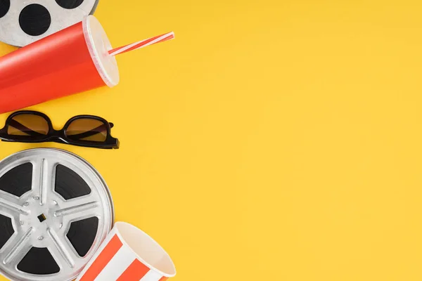 Bobinas de filme, óculos 3d, balde de pipoca e copo descartável vermelho com palha isolada em amarelo — Fotografia de Stock