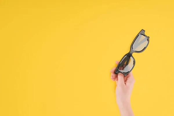 Visão recortada da mão feminina segurando óculos 3d estereoscópicos isolados no amarelo — Fotografia de Stock