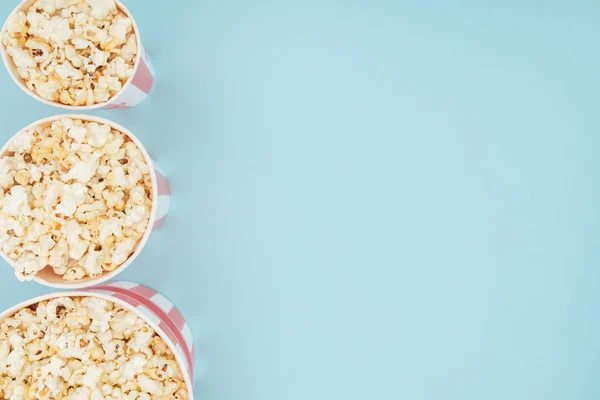Top view of buckets with popcorn in vertical row isolated on blue — Stock Photo