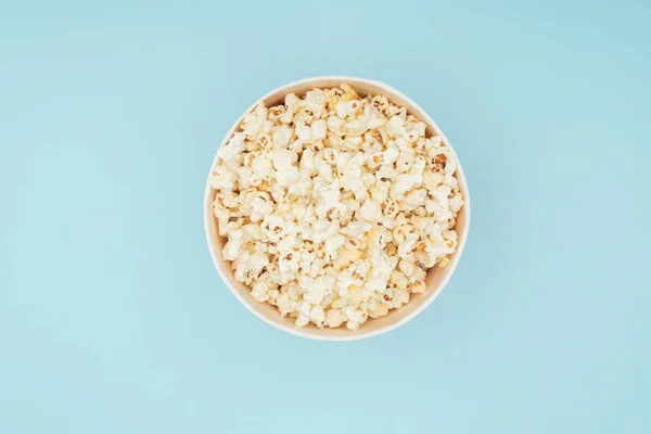 Top view of bucket with fresh tasty popcorn isolated on blue — Stock Photo