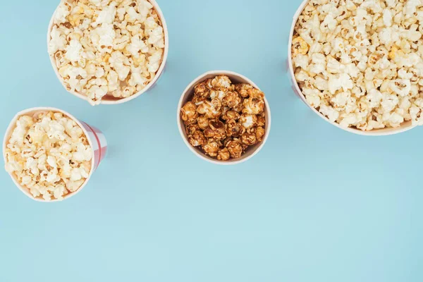 Draufsicht auf gestreifte Eimer mit frischem Popcorn isoliert auf blau — Stockfoto