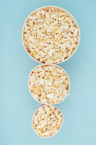 Top view of popcorn buckets of different sizes in vertical row isolated on blue — Stock Photo