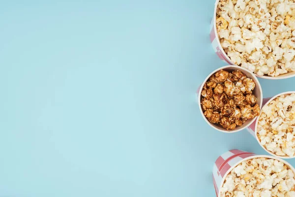 Top view of buckets with popcorn in vertical row isolated on blue — Stock Photo