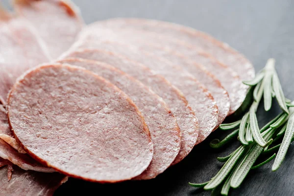 Close up view of rosemary and delicious sliced salami on table — Stock Photo