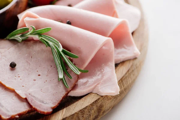 Vista da vicino del delizioso prosciutto affettato con spezie ed erbe su tagliere rotondo in legno — Foto stock