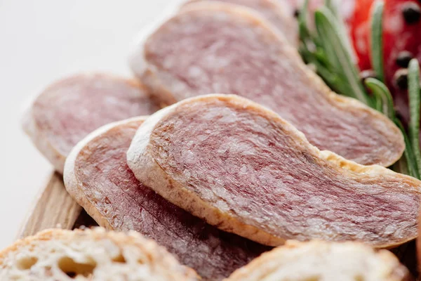 Vista de cerca de sabroso salami en rodajas con hierbas en la tabla de cortar - foto de stock