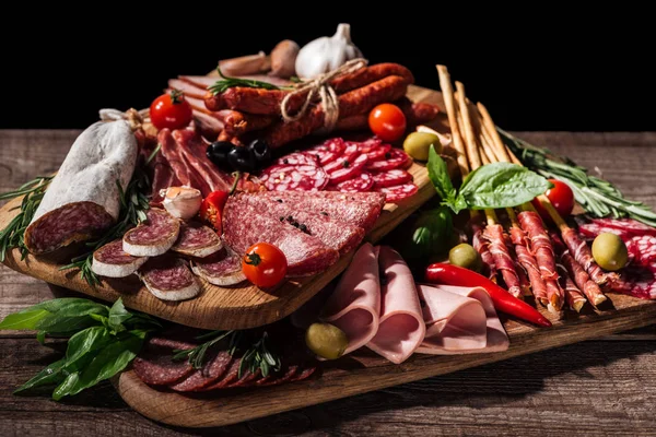Planches à découper avec délicieux salami, saucisses fumées, jambon et légumes sur table rustique en bois — Photo de stock