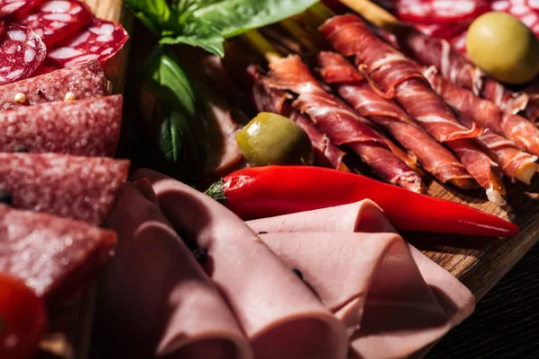 Close up view of delicious sliced salami and prosciutto with vegetables and spices — Stock Photo